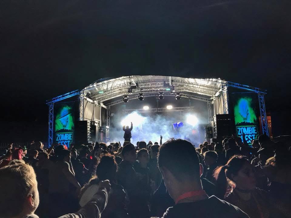 Zombie Fest main stage at night with crowd, LED screens showing the ZF logo and blue truss lighting