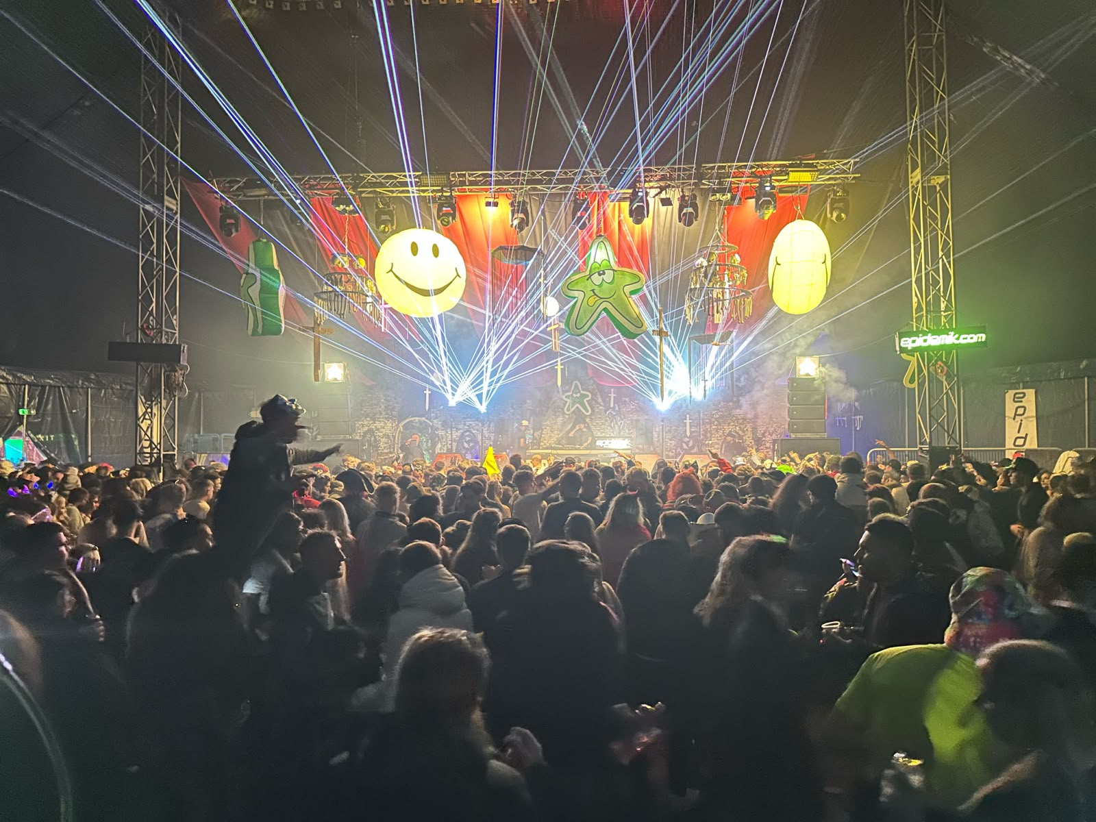 Epidemik stage inside the arena with laser fans, giant smiley and star inflatables and a full crowd at Zombie Fest